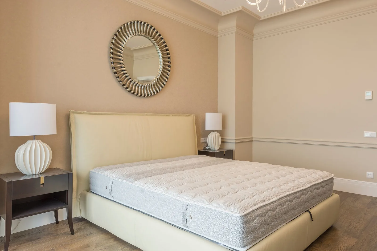 A bare mattress on a bed in a tidy bedroom.